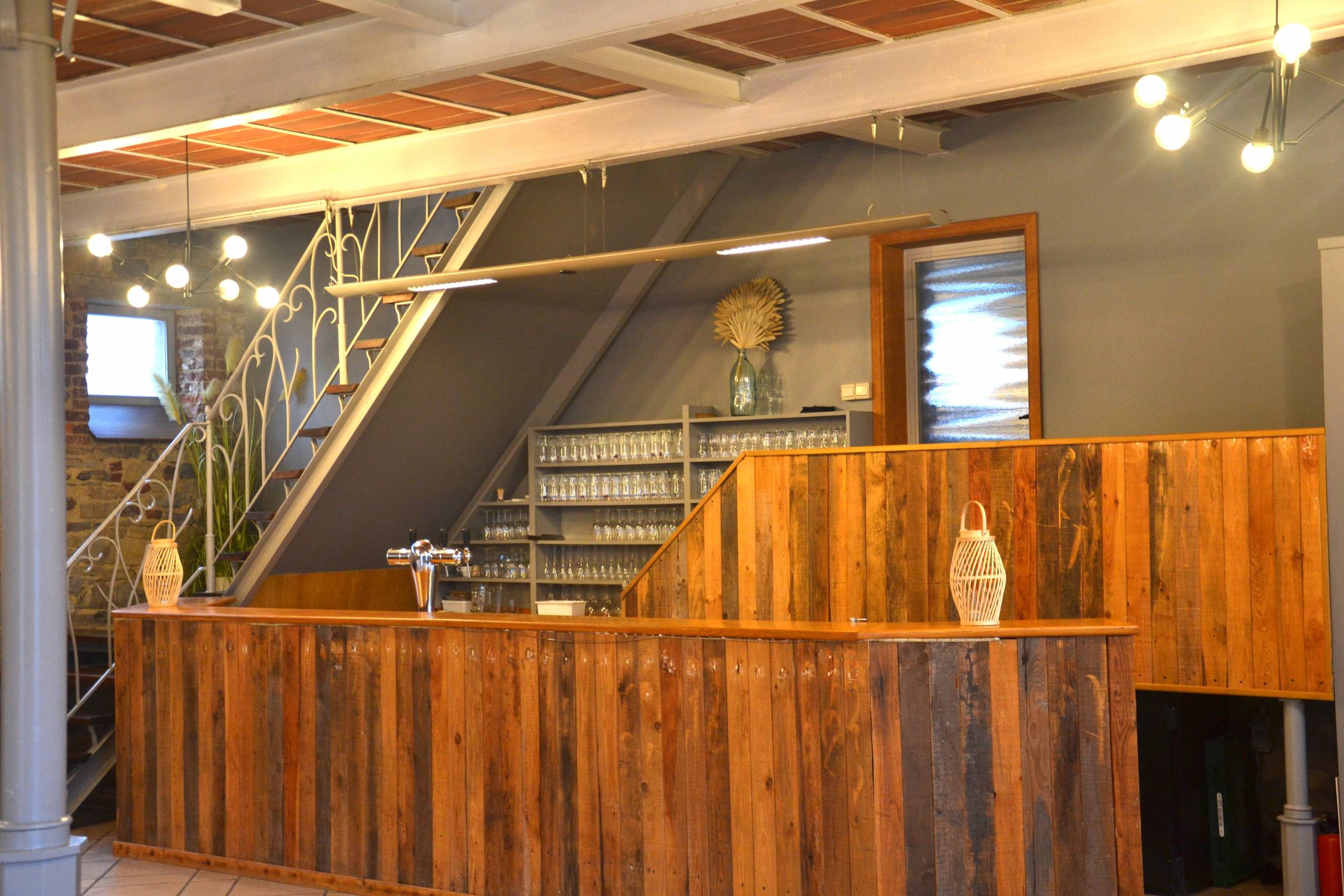 Le bar en bois au fond de la salle, et l'escalier métallique vers l'étage.
